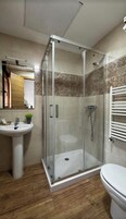 Un baño con ducha de vidrio, lavamanos e inodoro.