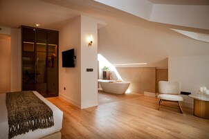 Un dormitorio moderno con una cama grande, un televisor, un vestidor y un baño con bañera.
