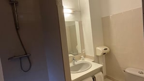 A bathroom with a shower, sink, mirror, and toilet. - Hotel De La Tour Saint Etienne SUD (Saint-Etienne)