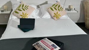 A hotel room with a bed, pillows, a bedside table with a lamp, a phone, and a laptop. - Hotel De La Tour Saint Etienne SUD (Saint-Etienne)