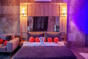 A hotel room with a large bed, a wooden headboard, a sofa, and a mirror. - 216 North Hotel - Agva (Şile)