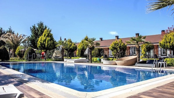A rectangular swimming pool with a tiled edge, surrounded by lounge chairs and a wooden deck. - 216 North Hotel - Agva (Şile)