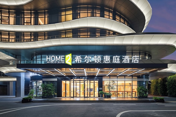 Un hotel moderno con fachada curva, amplia entrada de vidrio y un letrero que indica que es un hotel.