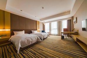 Ein Hotelzimmer mit zwei Betten, einem Schreibtisch, einem Stuhl und einem Fernseher.