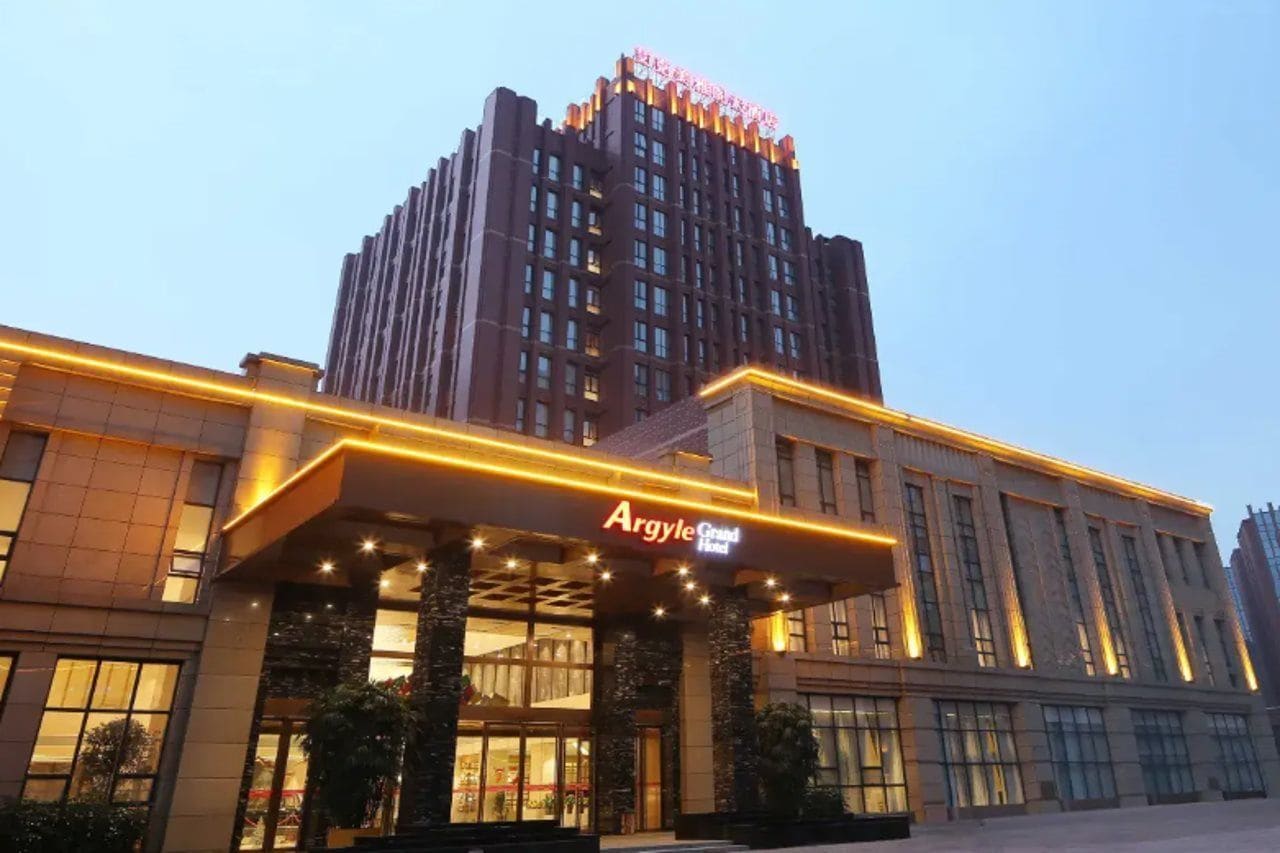 Un hotel con una entrada destacada y un edificio alto al fondo.