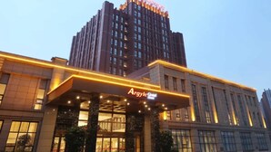 Een hotel met een opvallende ingang en een hoog gebouw op de achtergrond.