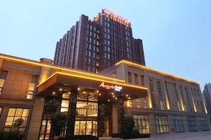 Ein Hotel mit einem markanten Eingang und einem hohen Gebäude im Hintergrund.