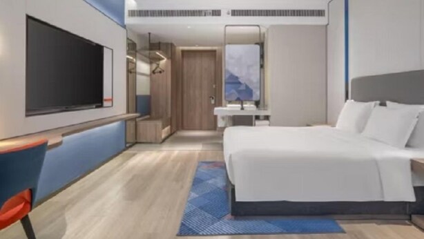 A modern hotel room with a large bed, a flat-screen TV, a desk, and a bathroom with a mirror. - Holiday Inn Express Nanchang High-tech Zone (Nanchang)