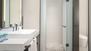 Ein modernes Badezimmer mit Waschbecken, Spiegel und einer Duschkabine aus Glas.