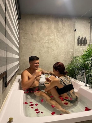 Una bañera con pétalos de rosa, una toalla y una botella de loción.