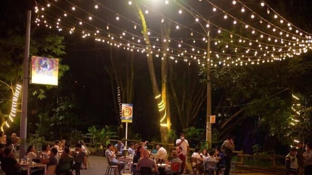 An outdoor dining area with string lights overhead, surrounded by trees. - Inactivo Hotel Natura Express (Medellín)