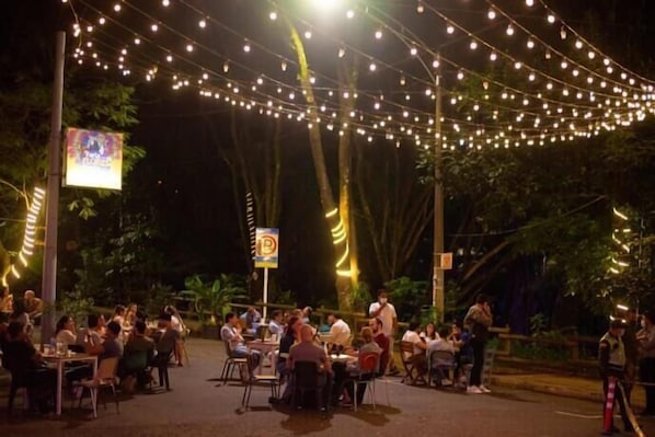 An outdoor dining area with string lights overhead, surrounded by trees. - Inactivo Hotel Natura Express (Medellín)