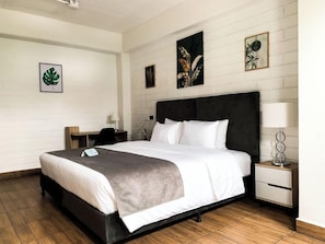 A neatly arranged bedroom with a bed, bedside tables, and artwork on the walls. - Inactivo Hotel Natura Express (Medellín)