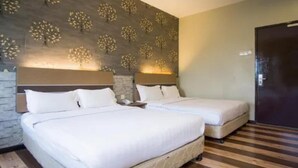 Quarto de hotel com duas camas, parede de destaque em tijolo e piso de madeira.
