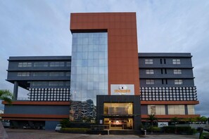 Ein modernes Hotel mit einem markanten, vertikalen orangefarbenen Bereich, einer reflektierenden Glasfassade und einem Schild mit der Aufschrift 'ENRISE'.