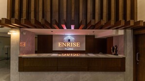 Un mostrador de recepción con un cartel que dice 'ENRISE by SAVALLI' y un techo de listones de madera encima.