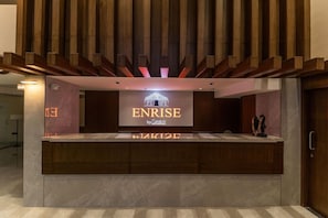 Ein Empfangsschalter mit einem Schild, das 'ENRISE by SAVALLI' zeigt, und eine Holzdachverkleidung darüber.