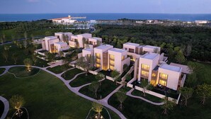 Ein moderner Hotelkomplex mit mehreren Gebäuden, angelegten Gärten und Blick auf das Meer.
