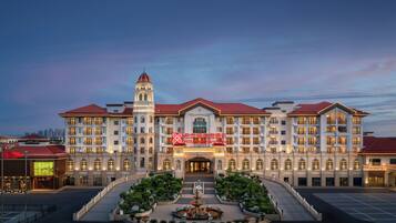 A large, multi-story hotel with a central courtyard, a prominent tower, and a well-lit entrance.