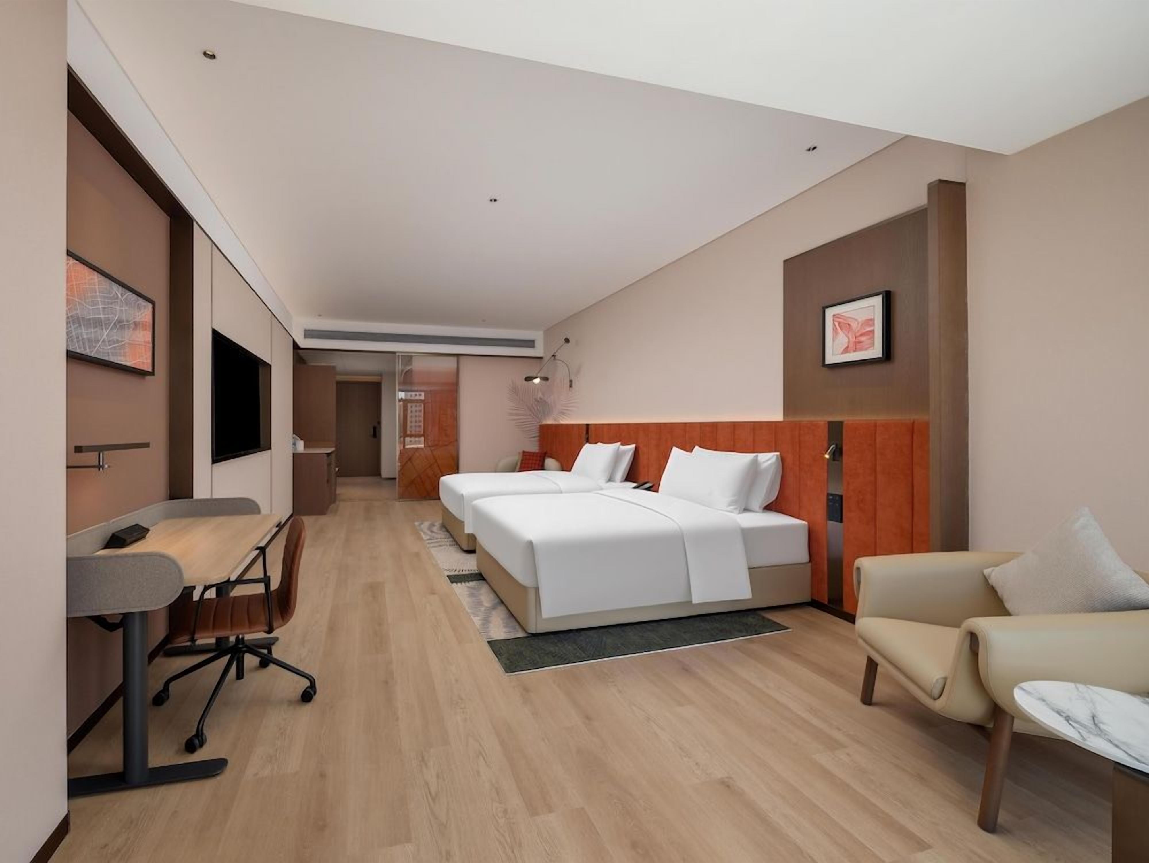 Une chambre d’hôtel avec un lit, un bureau, une chaise et un téléviseur.