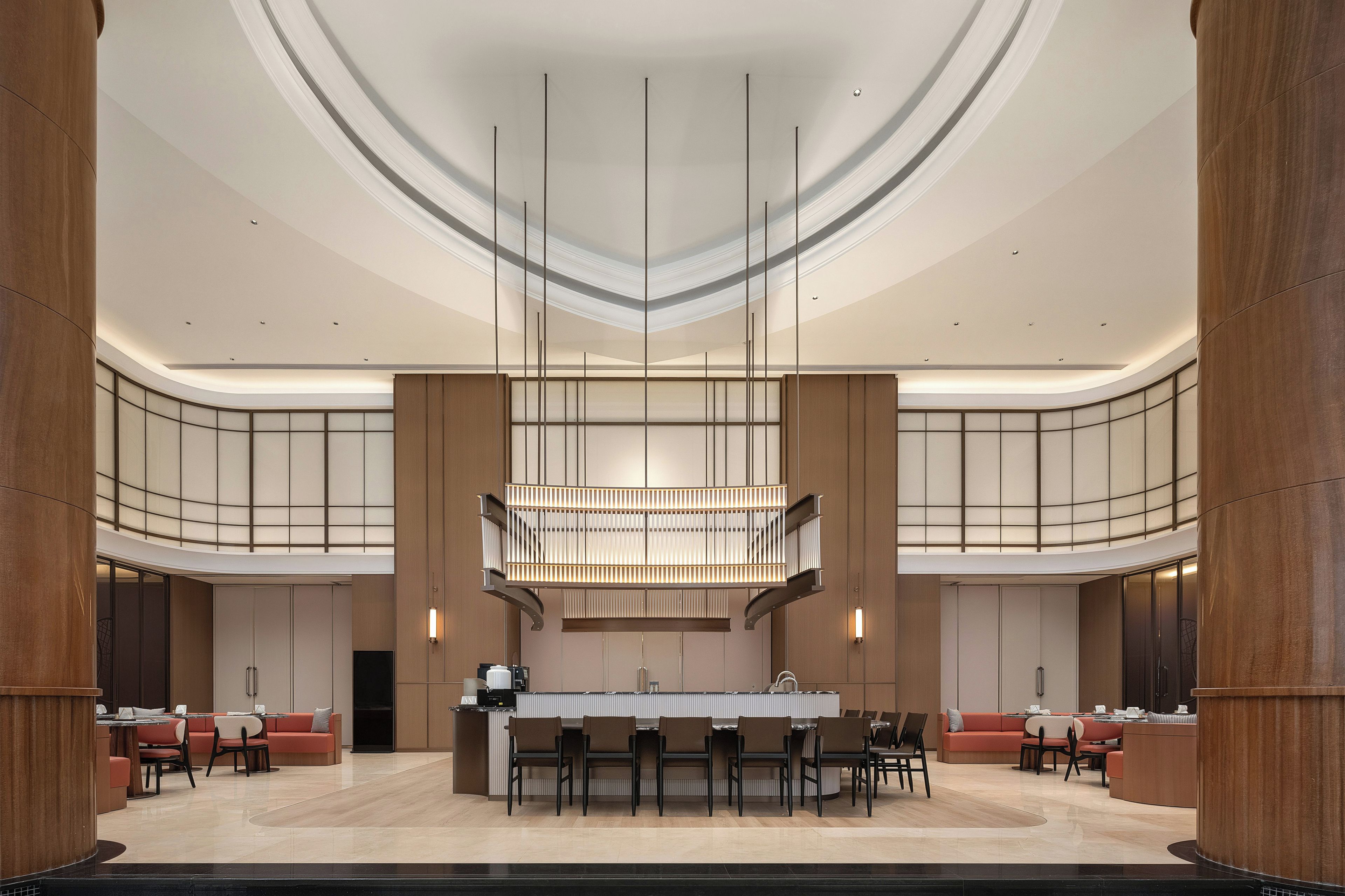 A spacious lobby with a central island, seating arrangements, and a modern chandelier.