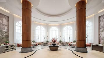 Eine geräumige Lobby mit hohen Decken, großen Holzsäulen und einer zentralen Fontäne.