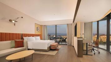 Une chambre d’hôtel moderne, dotée d’un grand lit, d’un bureau, d’un canapé et offrant une vue sur la ville.