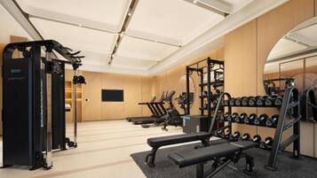 A gym with weightlifting equipment, treadmills, and a bench.