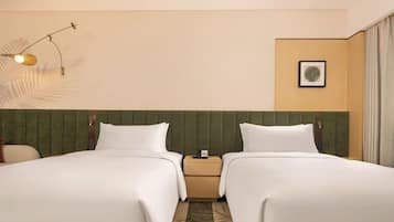 A hotel room with two beds, a nightstand, a lamp, and a framed picture on the wall.