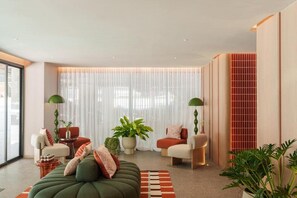 A modern living room with a sofa, chairs, a coffee table, and a large window with sheer curtains. - The Akyra Bangkok 11 (Bangkok)