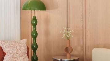 A modern living room with a sofa, a chair, a green floor lamp, and a small table with a vase.