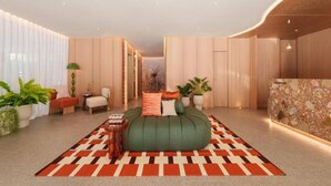 A modern hotel room with a green sofa bed, a patterned rug, and a stone accent wall. - The Akyra Bangkok 11 (Bangkok)
