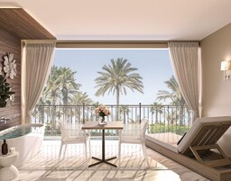 Un balcón con vista a palmeras, un espacio de estar con mesa y sillas y una bañera.