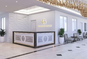 Un área de recepción con diseño moderno, que incluye mostrador de recepción, zona de estar y techo decorativo.