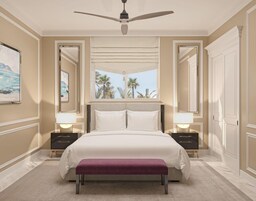 Un dormitorio con una cama grande, dos mesitas de noche, un ventilador de techo y vistas a palmeras.