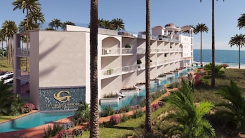 Un hotel de varios pisos con piscina, palmeras y vista al océano.