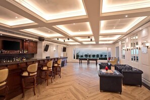 A bar area with a pool table and seating, a large TV screen, and a view of the outdoors. - Fortune Select Forest Hill Kasauli (Solan)