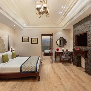 A hotel room with a bed, a desk, a fireplace, and a view through an open door. - Fortune Select Forest Hill Kasauli (Solan)