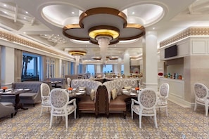 Eine luxuriöse Hotelhalle mit einer zentralen Sitzgruppe, eleganten Kronleuchtern und einem gemusterten Boden.