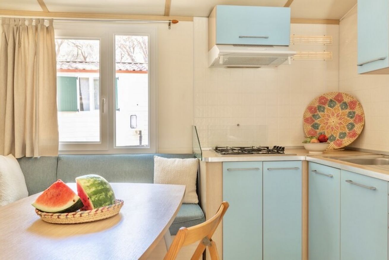A kitchen with a dining area, a stove, cabinets, and a window with a view.
