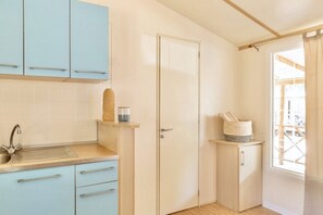 A kitchen with light blue cabinets, a sink, and a window with curtains.