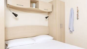 A bedroom with a bed, a headboard, a wardrobe, and two wall-mounted lamps.