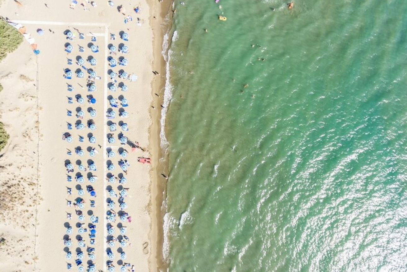 Una spiaggia con file di ombrelloni e lettini.