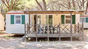 A mobile home with a porch and a covered area, surrounded by trees.