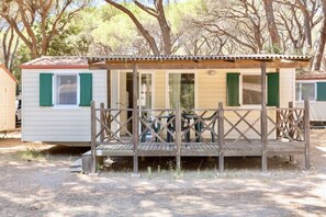 A mobile home with a porch and a covered area, surrounded by trees.
