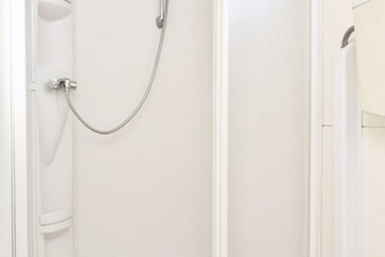 A white bathroom with a shower enclosure and a door.