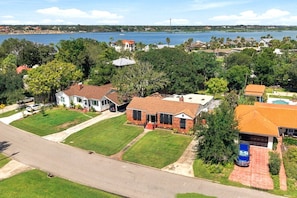 A residential area with houses, a road, and a body of water in the background. - Island Cottage, Fenced Yard, Huge Porch, Game Room, Fire Pit, Walk/Bike Downtown, $300 Free Tickets! (St. Augustine)