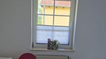 A room with a window, a radiator, a red chair, and a bed.