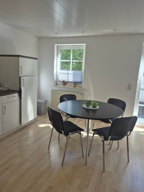 Eine moderne Küche mit weißen Schränken, einem eingebauten Kühlschrank und einem Fenster mit Jalousien.