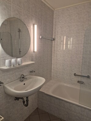 Ein Badezimmer mit Waschbecken, Spiegel und Badewanne.